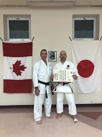 two men posing in front of a canadian and japanese flag